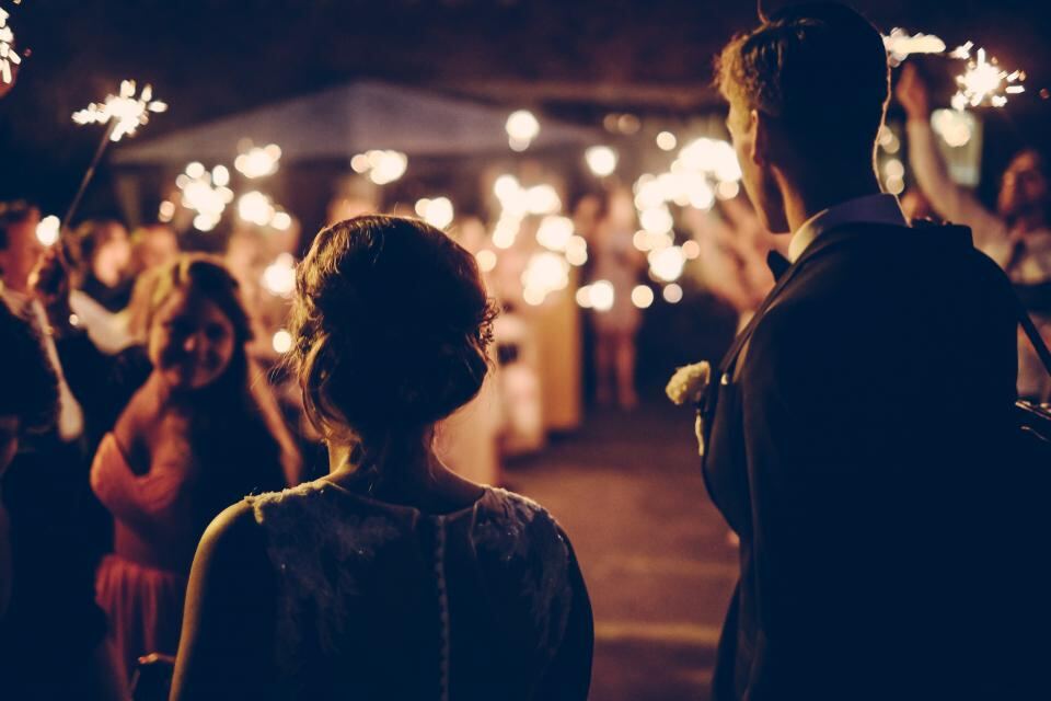 Novios caminando entre luces de bengala en su fiesta de boda