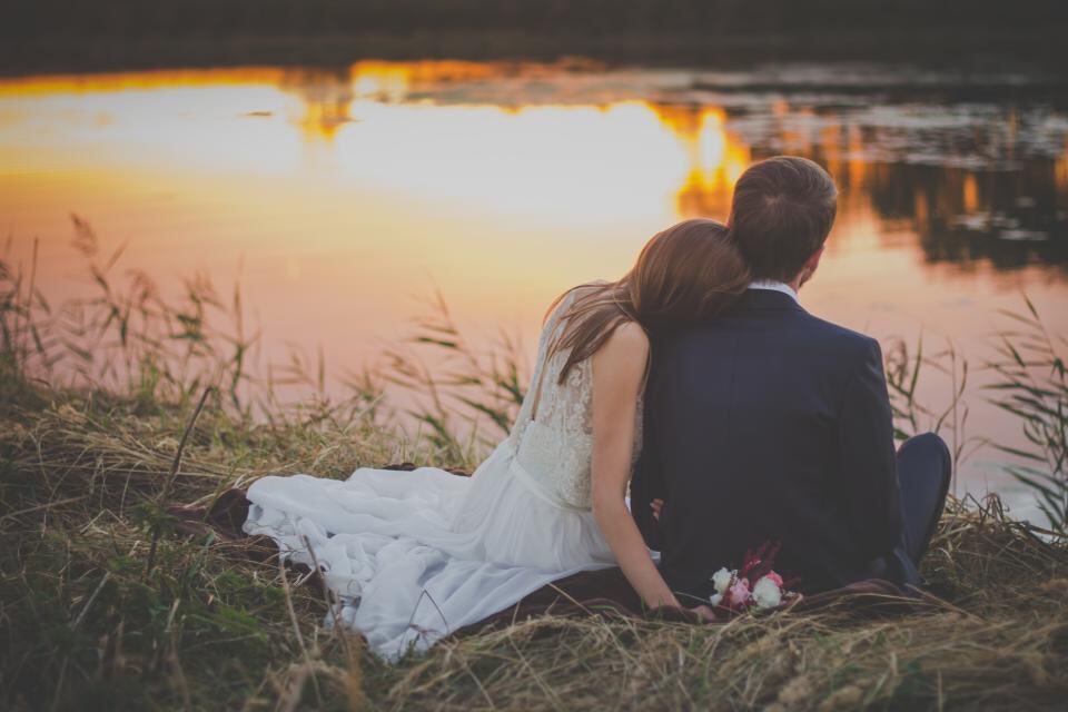 Novios abrazados frente al lago al atardecer